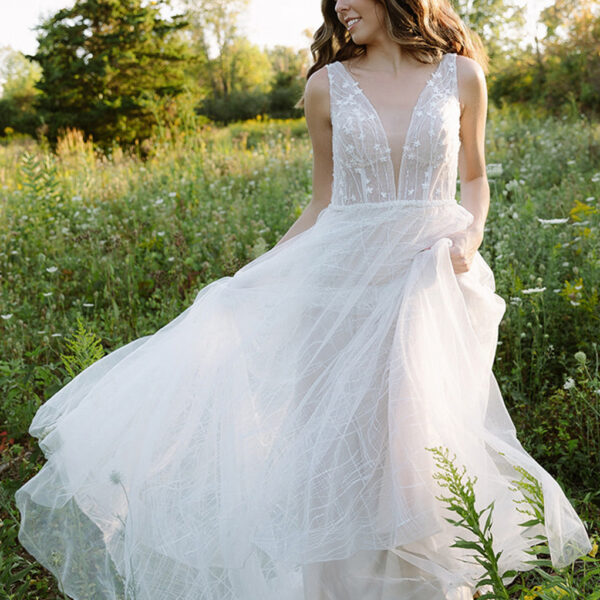 floor-length tulle dress. This romantic dress is lined with a built-in bra and is held in place by sleeveless sheer straps and a zipper at the back. It is magnificently patterned afte