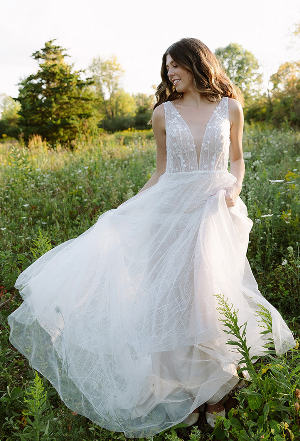 floor-length tulle dress. This romantic dress is lined with a built-in bra and is held in place by sleeveless sheer straps and a zipper at the back. It is magnificently patterned afte