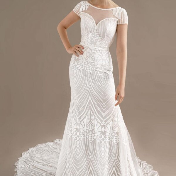 The Lottie wedding gown features a simply radiant design that will take their breaths away. The illusion neckline is offset by pretty cap sleeves. The train of the dress adds that graceful charm that you deserve on your wedding day. The design of the fabr