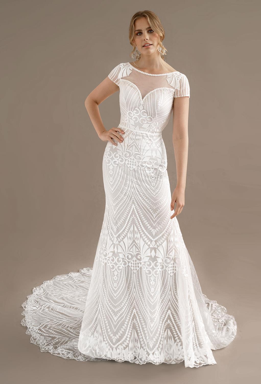 The Lottie wedding gown features a simply radiant design that will take their breaths away. The illusion neckline is offset by pretty cap sleeves. The train of the dress adds that graceful charm that you deserve on your wedding day. The design of the fabr