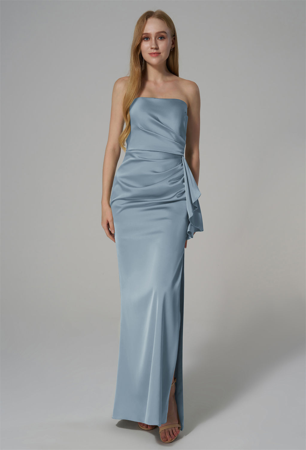 featuring a strapless neckline and a floor-length silhouette. The design is enhanced by elegant draping and a side slit for added sophistication. Crafted from high-quality satin fabric