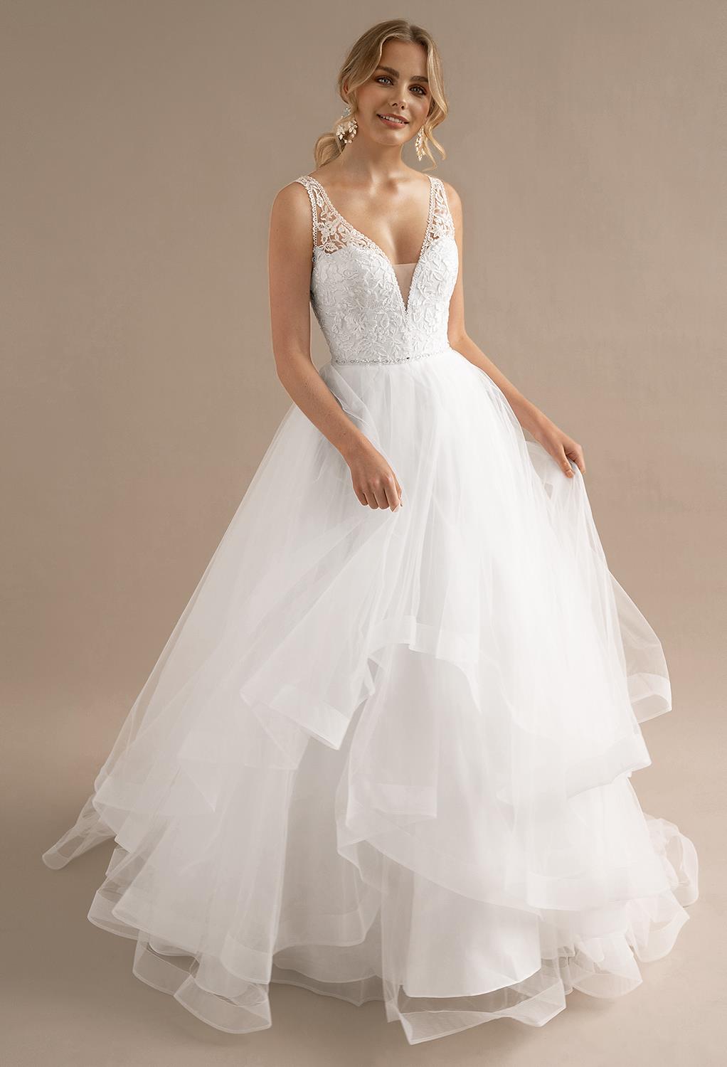 Flirty and playful layers of tulle come together in the Beverly wedding gown. Pleats and layers offer graceful and playful movement. The plunging neckline and bared back of the gown adds a delightfully romantic touch to the dress. The dress features elega