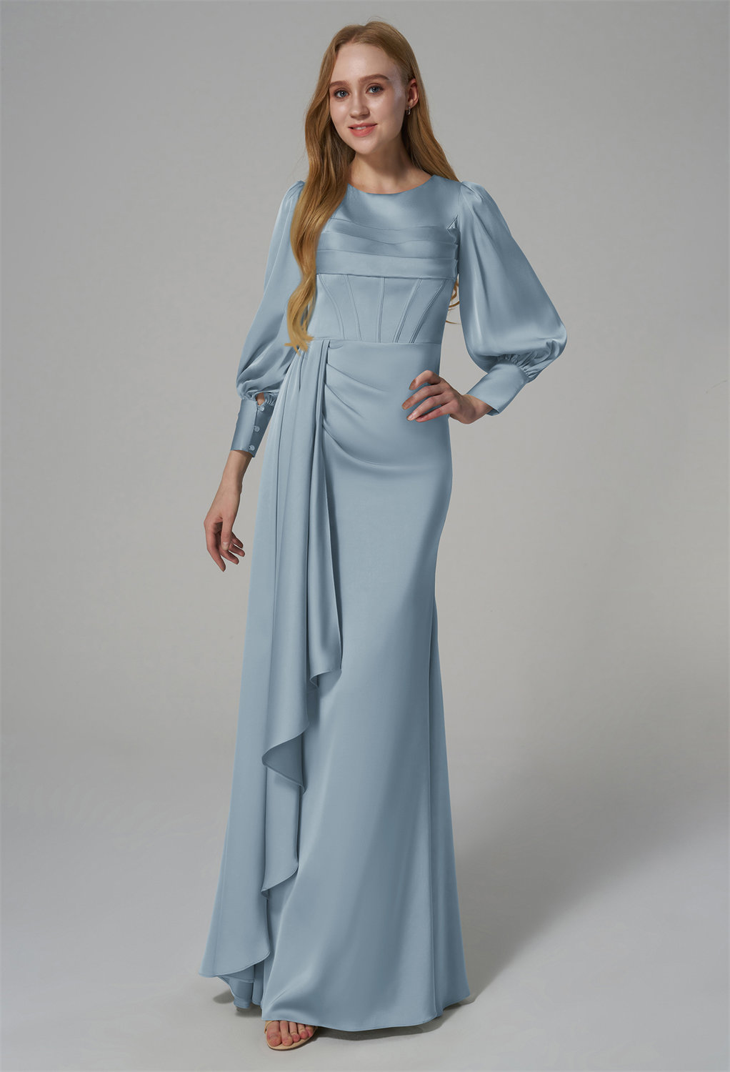 puffed sleeves and a fitted bodice with draped detailing at the waist. The floor-length skirt is complemented by a cascading side panel