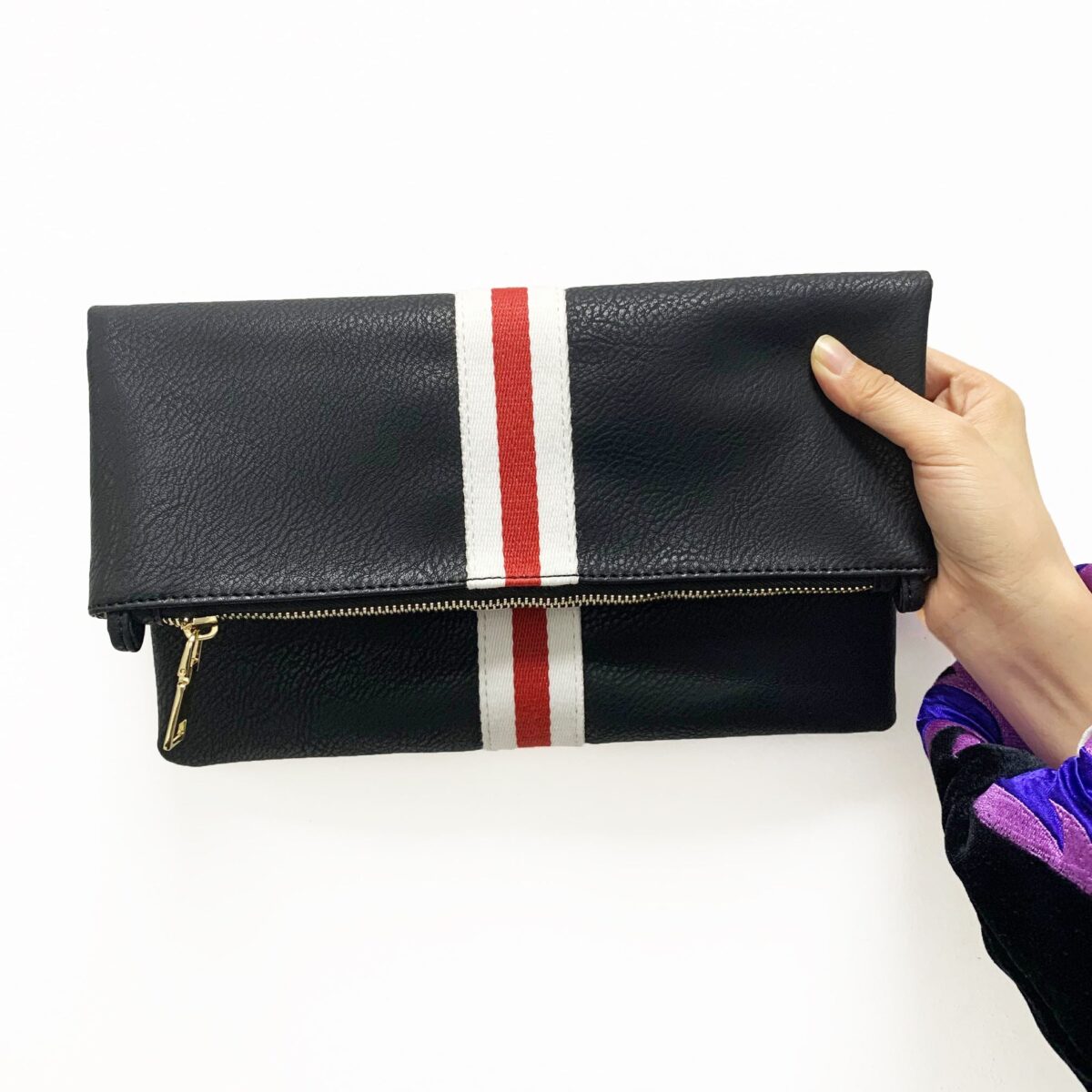 Our beautiful Toni Fold Over Clutch from the Threaded Pear is the perfect take anywhere bag. The stunning vegan leather bag with accent stripe features a zipper closure to access the a smart interior for all your must-have essentials. Fold over or carry